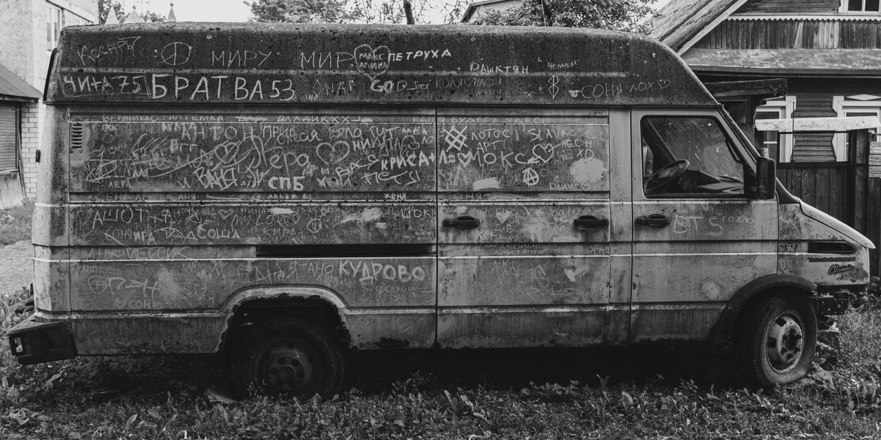 A weathered van covered in graffiti, captured in monochrome, symbolizing urban decay.